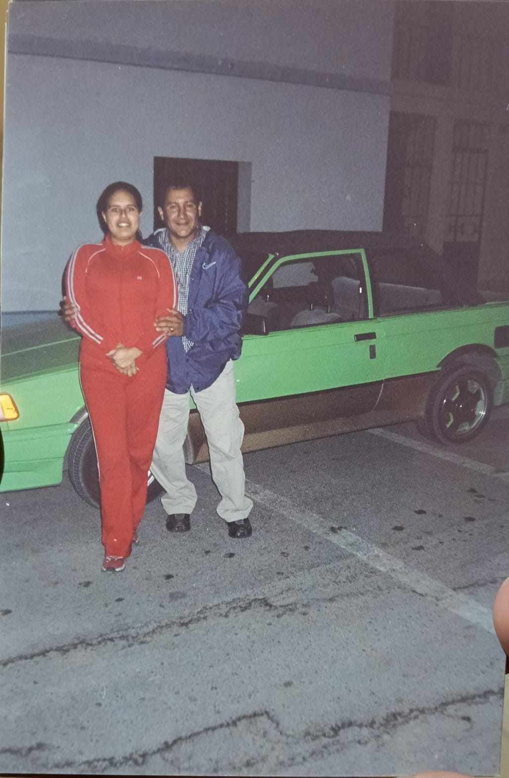 Dos amigos juntos junto a un automóvil verde durante la noche